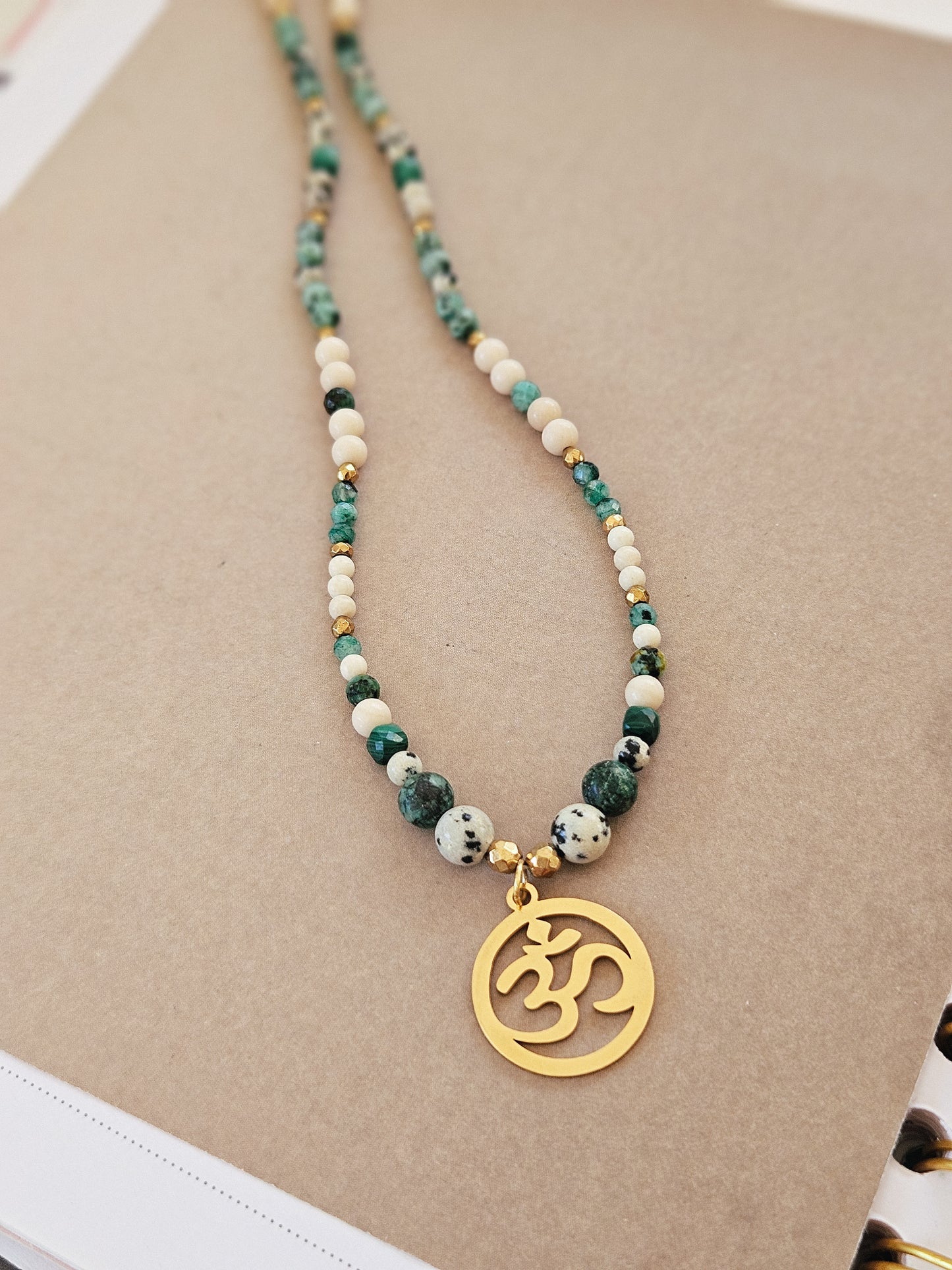 Collar elaborado con Piedras Naturales: Malaquita, Turquesa Africana, Piedra de Río, Jaspe Dálmata y Hematites con colgante del Signo "Om"